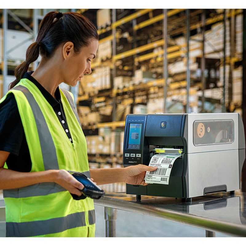Operaria usando impresora de etiquetas Zebra en almacén de logística y distribución